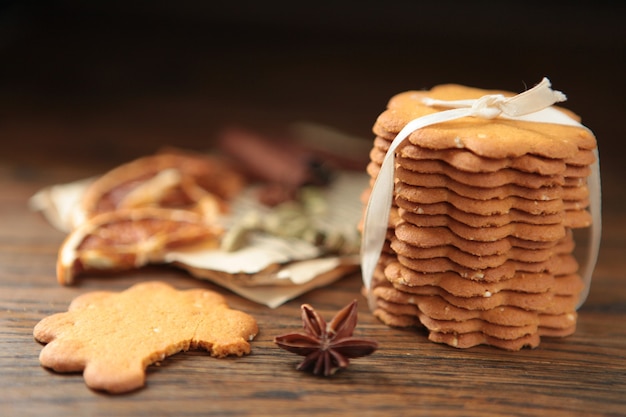 Homemade tasty gingerbread cookies on dark wooden table with dried oranges cinnamon stick paper