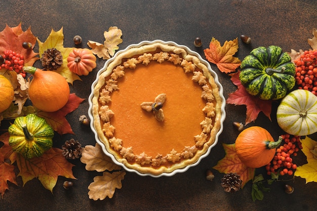 Homemade tasty pumpkin pie with autumn decorations and leaves for thanksgiving day on white