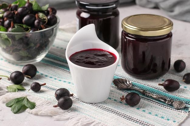 Marmellata di yoshta spessa fatta in casa in ciotola e vasetti di vetro su sfondo grigio