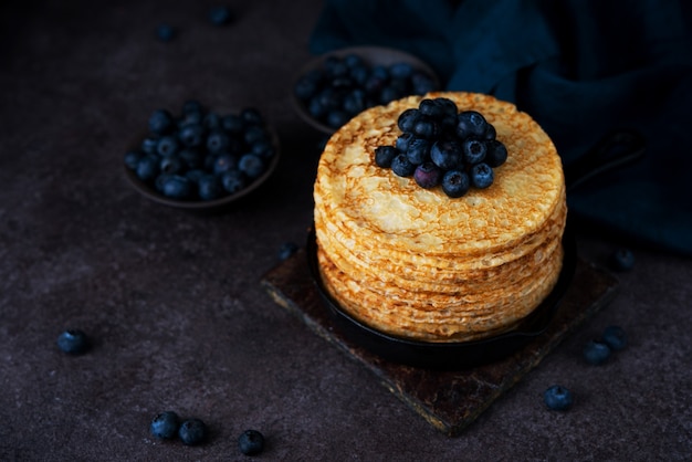 Homemade thin pancakes in a frying pan with blueberries, maslenitsa