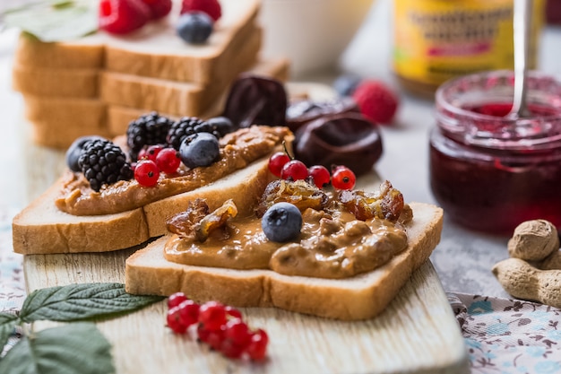 朝食の木製テーブルにジャムとピーナッツバターと自家製トーストパン。おいしいトーストパン。朝食用スプレッドのトーストパン。