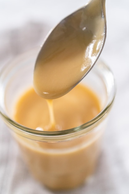 Homemade toffee glaze in a glass jar on the kitchen counter.