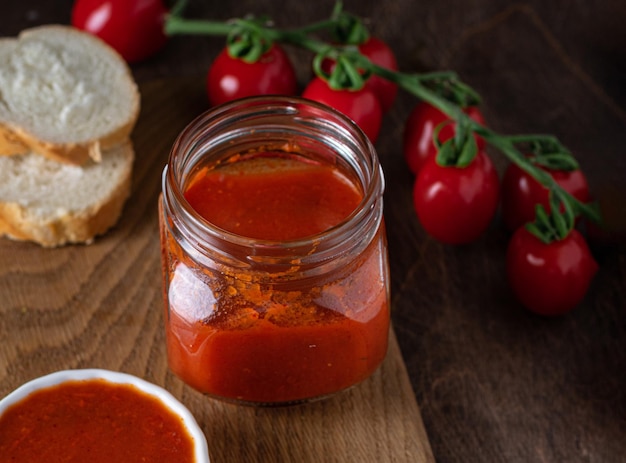 Homemade tomato chutney in glass jar on wooden background Selective focus Copy space