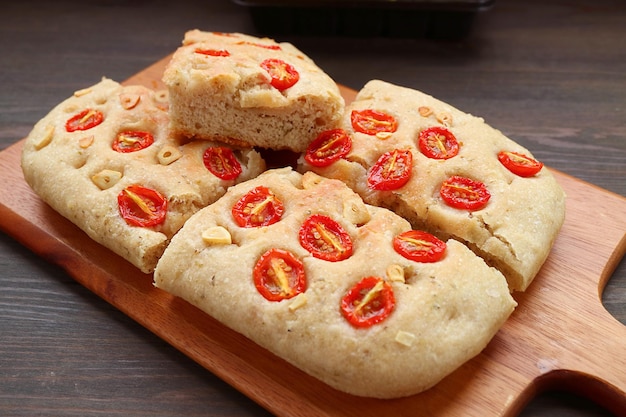 Homemade Tomato and Garlic Italian Focaccia Bread on Wooden Breadboard