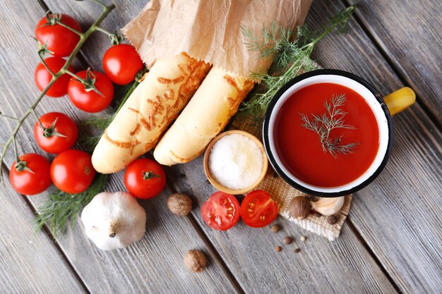 Homemade tomato juice in color mug bread sticks spices and fresh tomatoes on wooden background