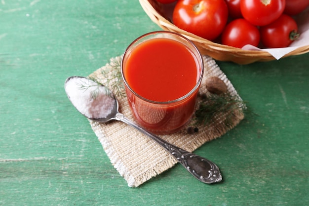 유리 향신료에 홈메이드 토마토 주스와 나무 배경에 신선한 토마토