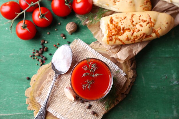 Succo di pomodoro fatto in casa in vetro, spezie e pomodori freschi su fondo in legno