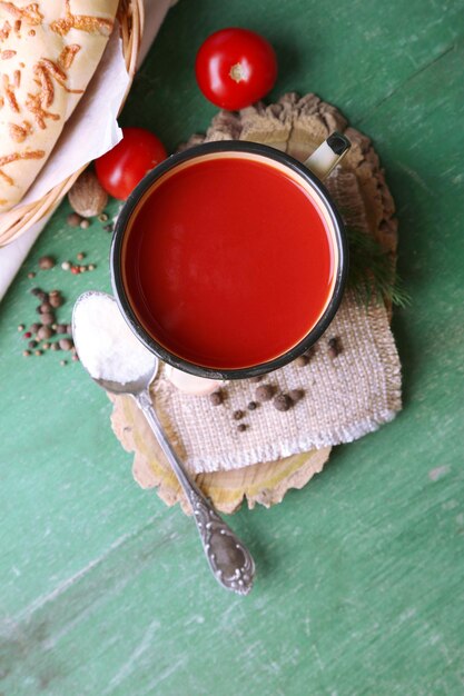 Homemade tomato juice in mug spices and fresh tomatoes on wooden background