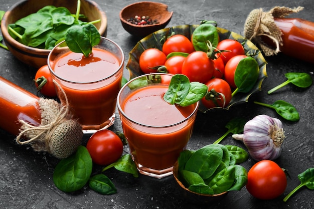 Homemade tomato juice with salt and spices in glasses Side view On a stone background