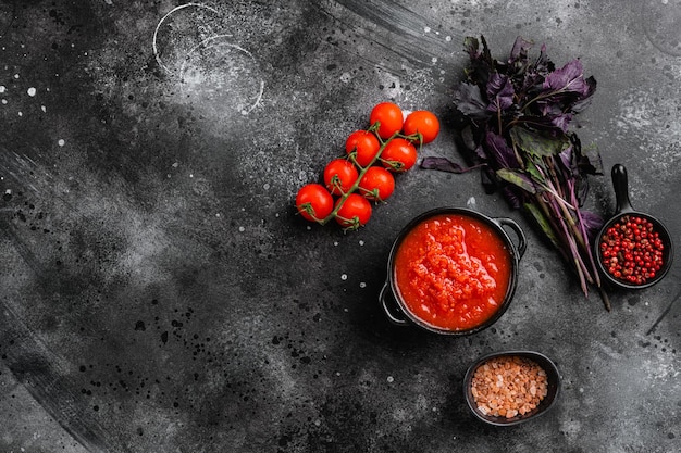 Домашний томатный соус пассата традиционный рецепт набора итальянской кухни, на фоне черного темного каменного стола, плоский вид сверху, с местом для копирования текста