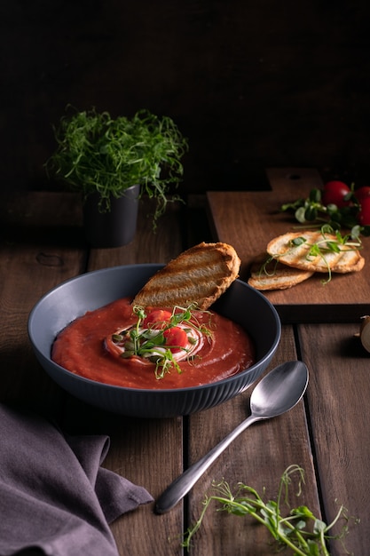 Homemade tomato soup in a blue bowl with toast bread on a wooden table