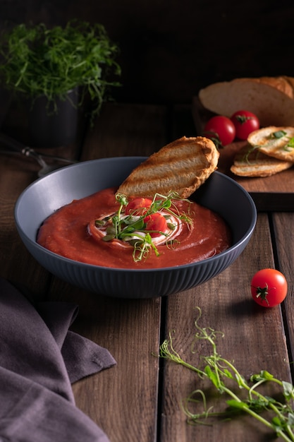 Homemade tomato soup in a blue bowl with toast bread on a wooden table