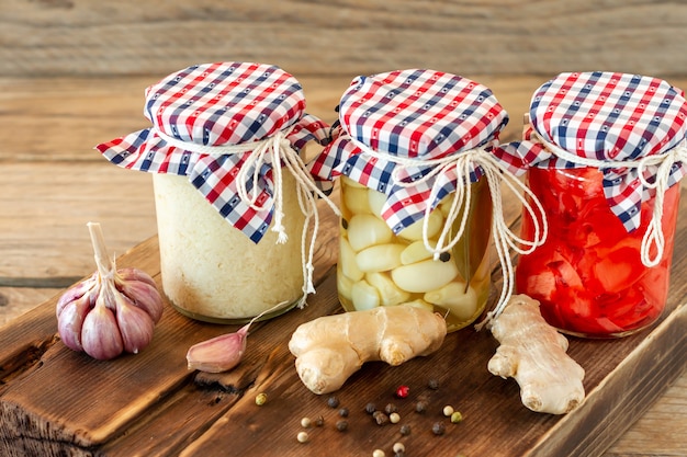 Homemade tomatoes preserves in glass jars in white wicker basket on wooden background.