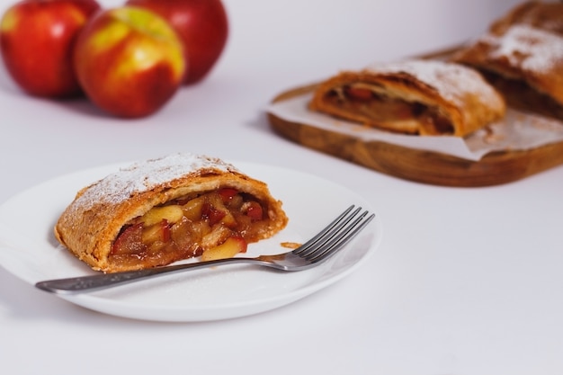 Foto strudel di mele tradizionale fatto in casa sul tavolo bianco.