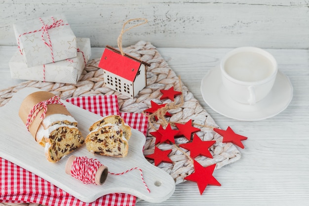 Dolce natalizio tradizionale fatto in casa stollen con bacche secche, noci e zucchero a velo in cima si leva in piedi sul tavolo in legno rustico bianco