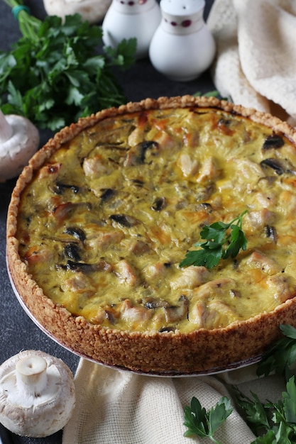 Homemade traditional French quiche with turkey mushrooms and cheese on a dark textured background