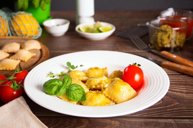 Homemade traditional italian ravioli pasta with basil and tomato cherry vegetables on the wooden table