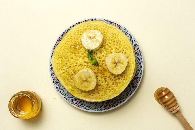 Homemade traditional moroccan baghrir with honey, strawberries and mint. Moroccan Pancakes from above