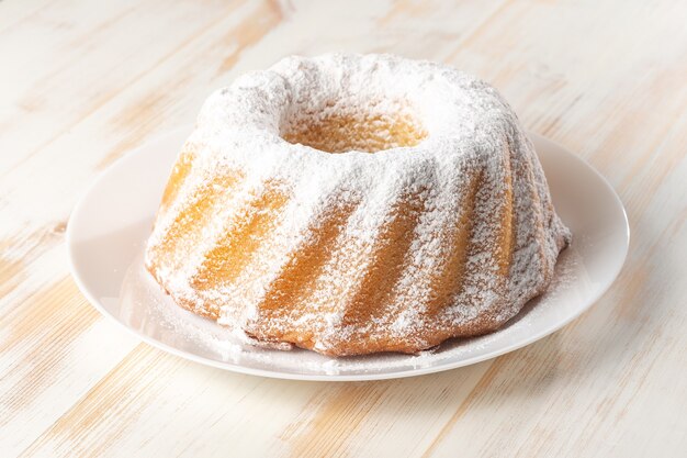 Homemade vanilla bundt cake on white wooden table