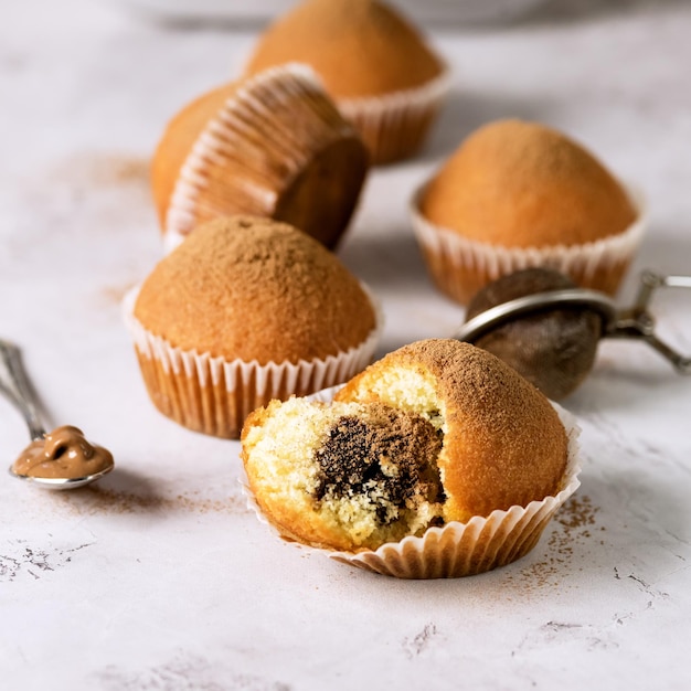 Muffin alla vaniglia fatti in casa cosparsi di glassa al cacao messa a fuoco selettiva quadrata