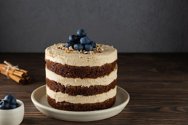 Homemade vegan carrot cake with cream and blueberries on a wooden table