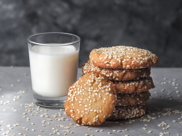 Biscotti fatti in casa di tahini vegani in pila con un bicchiere di latte