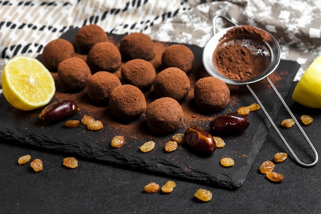 Homemade vegan truffles with dried fruits, walnuts and raw cocoa powder served on black slate plate