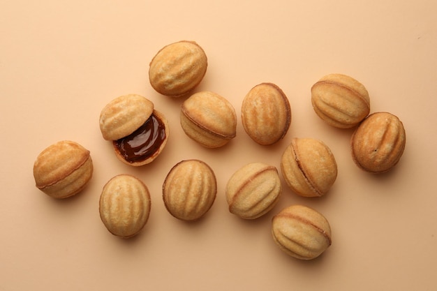 Homemade walnut shaped cookies with boiled condensed milk on beige background flat lay