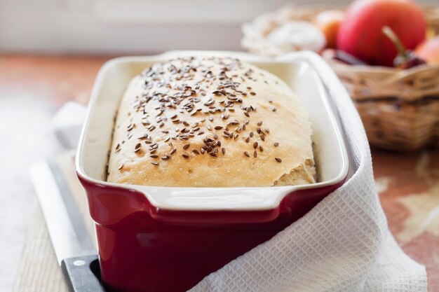 Homemade wheat bread with flax seeds in red ceramic baking dish