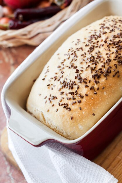 Homemade wheat bread with flax seeds in red ceramic baking dish