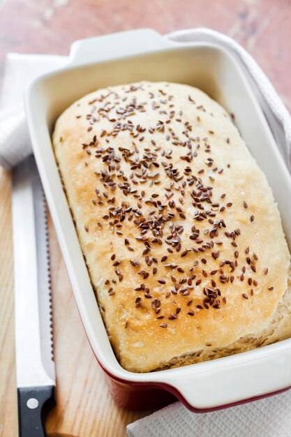 Homemade wheat bread with flax seeds in red ceramic baking dish