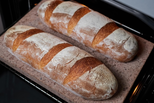 Homemade wheat loaves are baked in the oven on a baking stone