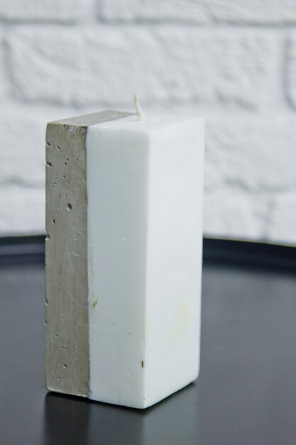 Homemade white candle with concrete on the surface of a white wall