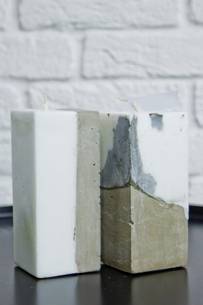 Homemade white candle with concrete on the surface of a white wall