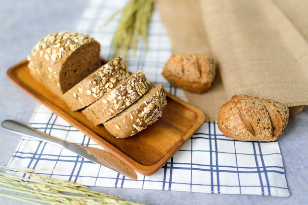 Homemade Whole Wheat Roggebrood Loaf wordt gesneden en op een houten bord gelegd. Leg het op een tafelkleed.