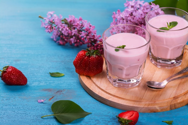 Homemade yoghurt with fresh strawberry and mint on blue wooden background