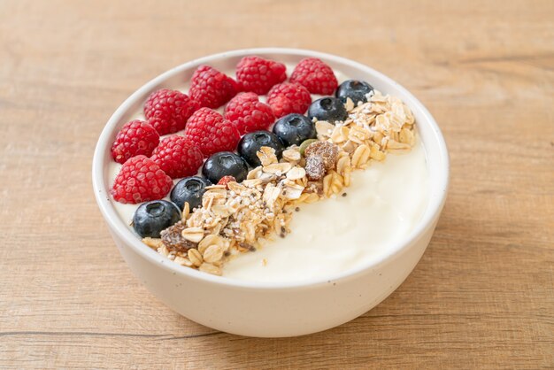 Ciotola di yogurt fatto in casa con lamponi, mirtilli e muesli - stile di cibo sano