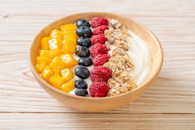 homemade yogurt bowl with raspberry, blueberry, mango and granola - healthy food style