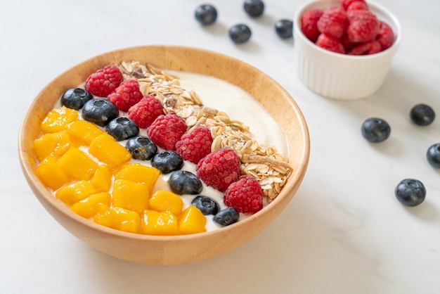 homemade yogurt bowl with raspberry, blueberry, mango and granola - healthy food style