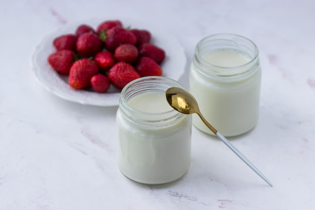 Homemade yogurt Jars of yogurt and strawberries on a white table Proper nutrition