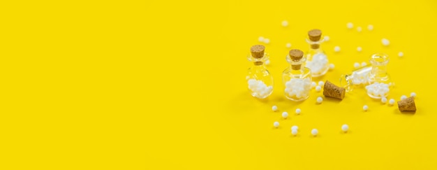Гомеопатическая стеклянная бутылка на желтом фоне. Альтернативная медицина лекарств гомеопатия, концепция здравоохранения