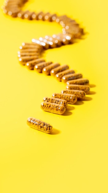 Photo homeopathic pills capsules with bee pollen on a bright yellow background natural