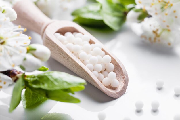 Homeopathic pills with spring flowers on white background