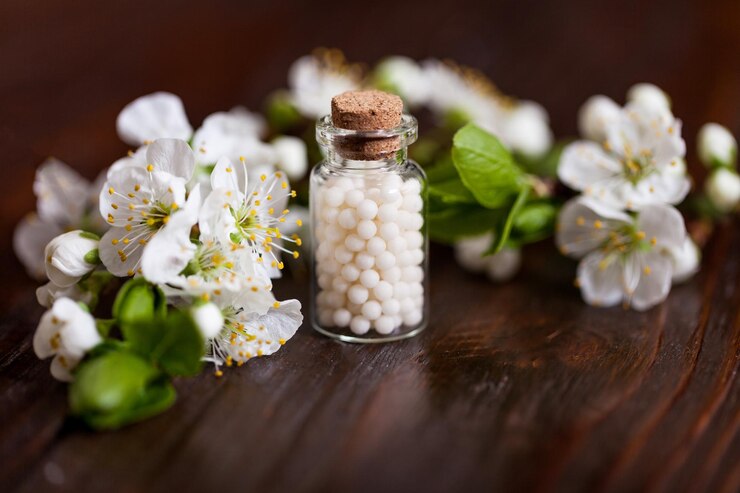 Photo homeopathic pills with spring flowers on white wooden background