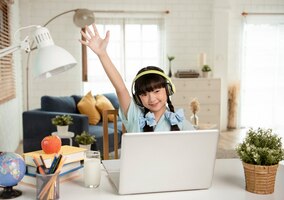 Homeschool asian little young girl student learning virtual internet online class on table at home.