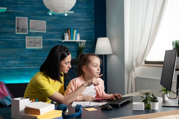 Homeschooled little kid getting assistance from mother