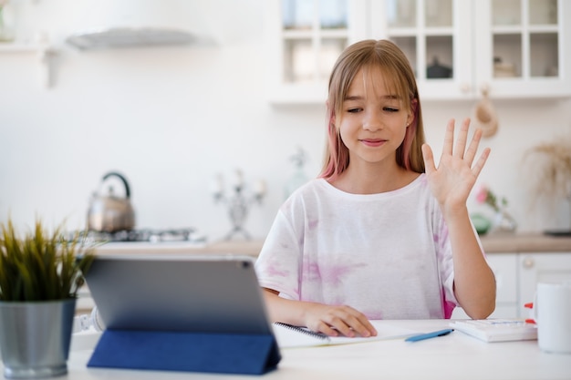 Homeschooled little young girl student having online class using digital tablet