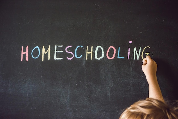 Homeschooling child pointing at word homeschooling on a blackboard