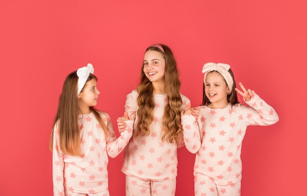 Фото Домашняя одежда и пижамы для детей. счастливые сестры в домашней одежде. держась за руки и давая v петь