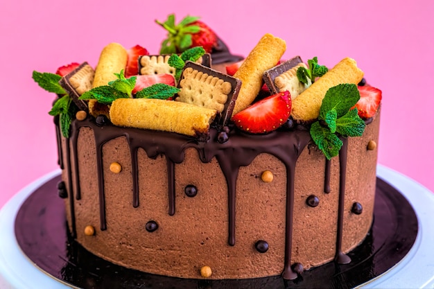 Hommade chocolate cake decorated with strawberries on a pink background